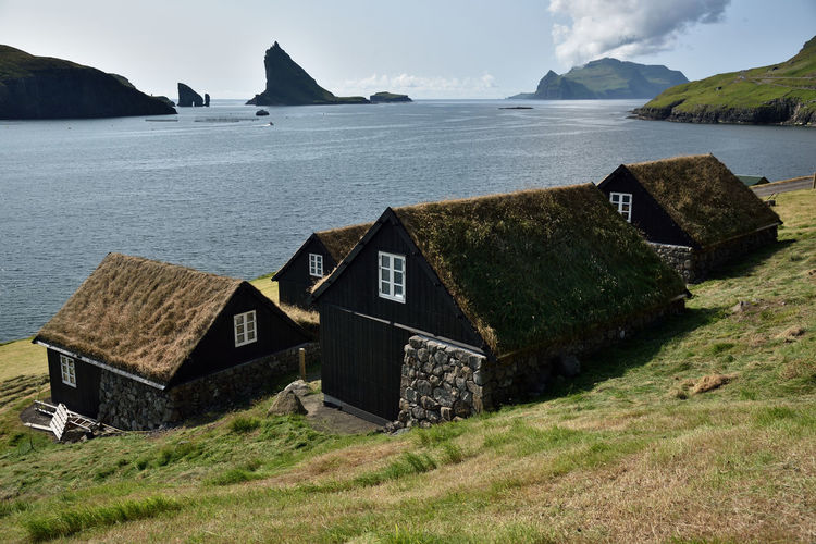 Scenic view of sea and houses against sky and dramatic faroese landscape