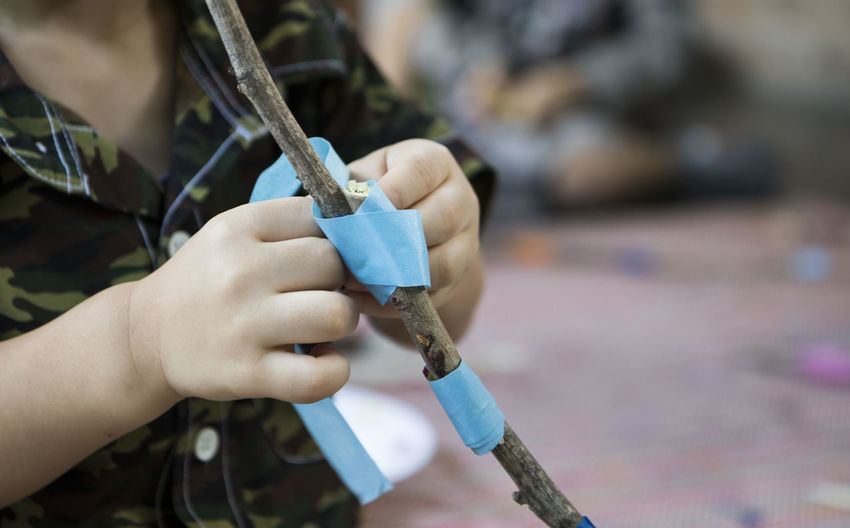Close-up of person tying sticks with adhesive tape