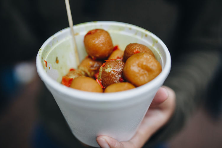Close-up of hand holding bowl of food