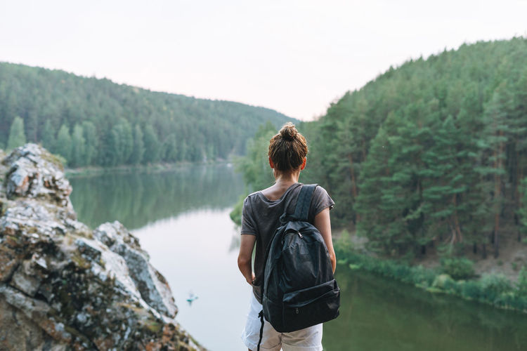 Young woman in casual with backpack looks at beautiful view of mountain and river, local travel