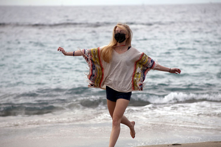 Young woman with arms outstretched walking at beach