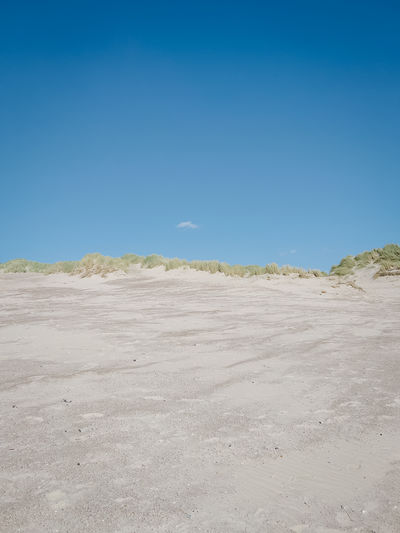 Scenic view of desert against clear blue sky