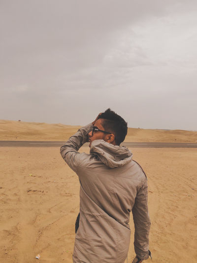 Man photographing on desert against sky