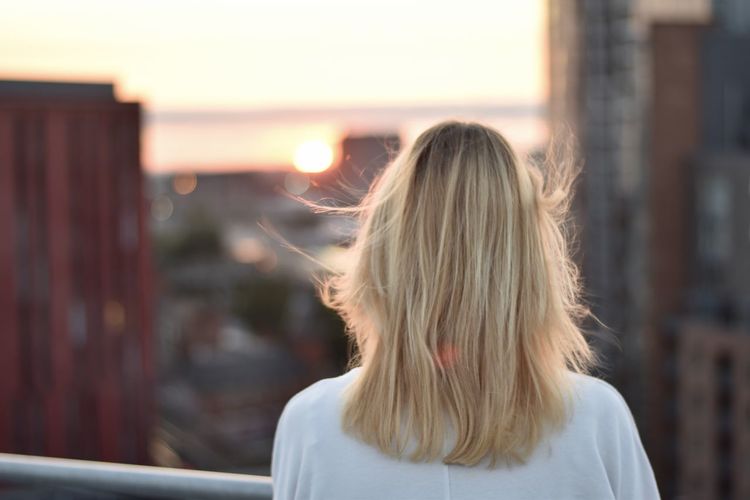 Rear view of woman standing at sunset