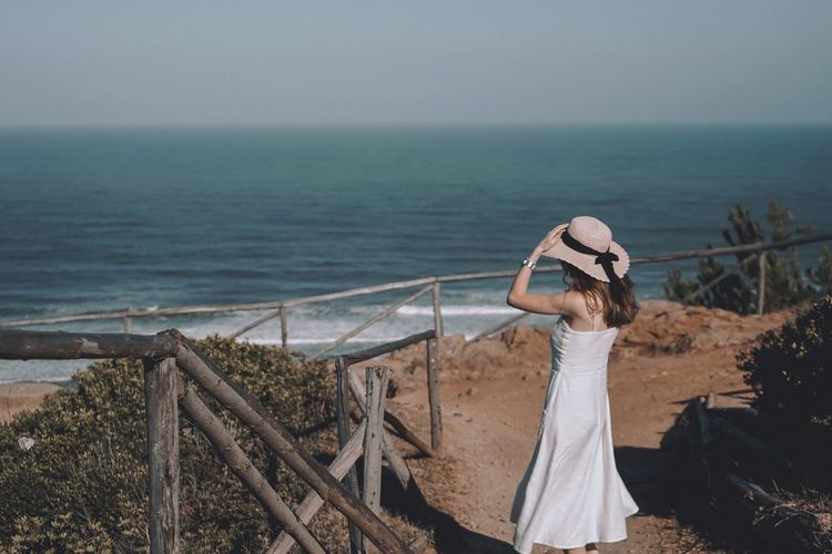 Woman standing at beach against sky