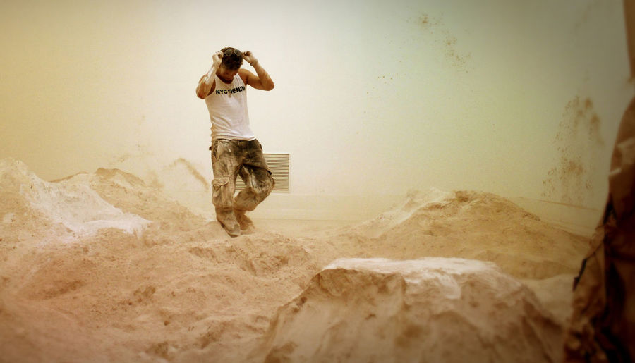 Full length of messy artist walking amidst powdered plaster at workshop