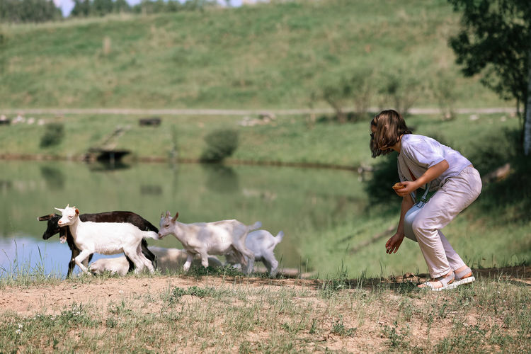 Side view of man with goat on field