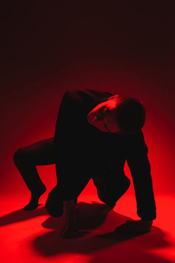 Side view of man sitting against red background
