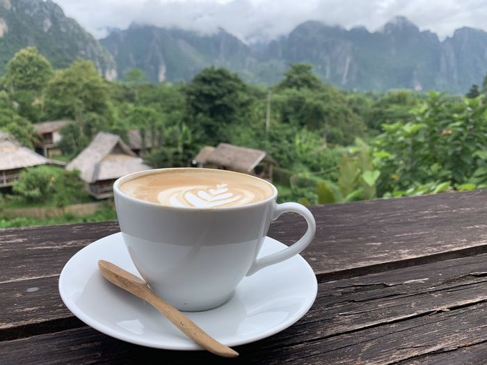 Coffee cup on table against mountains