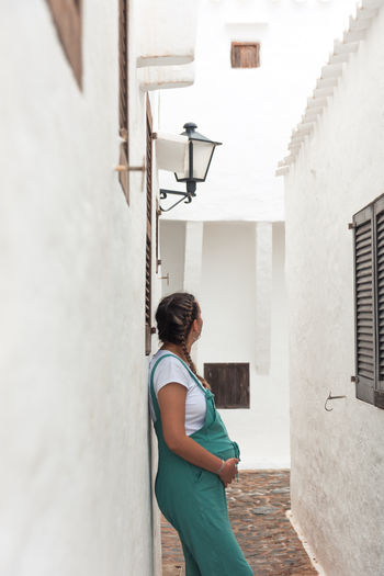 Young pregnant woman in a village of white houses on the island of menorca.