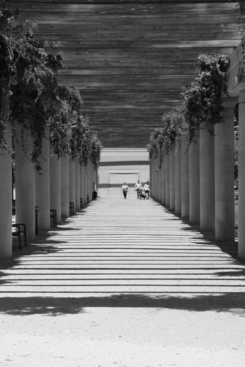 People walking on footpath amidst columns at parque lineal del rio manzanares