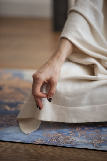 Midsection of woman doing yoga on mat at home