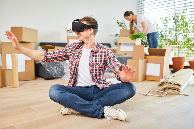 Full length of man using virtual reality simulator at home