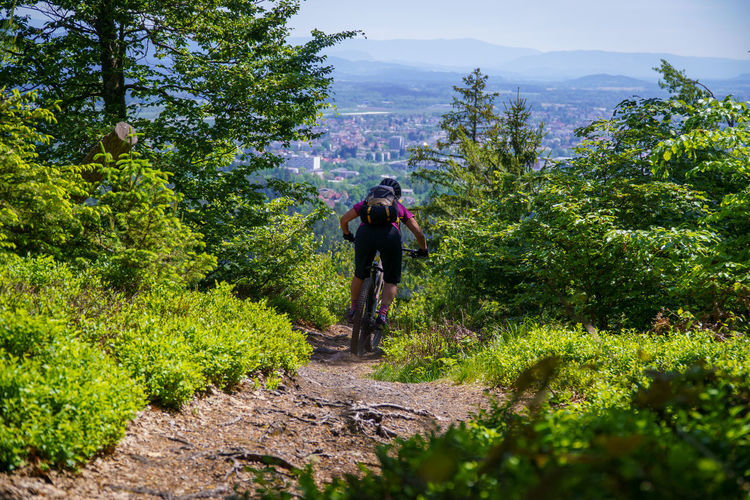 A young woman riding a mountain bike on a singletrail in the austrian alps near klagenfurt, austria.