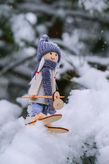 Angel gnome in scarf and knitted hat skiing on snowy fir branch elf toy on skis in snowy landscape