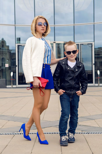 Young business woman in short blue trunks standing and waiting  the bank of glass and her son