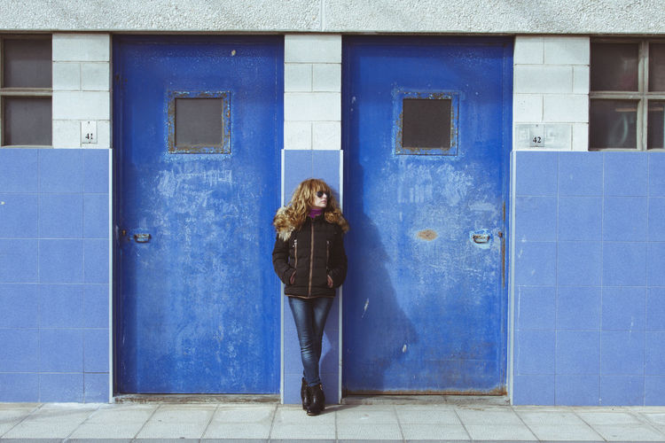 Portrait of woman standing against door of building