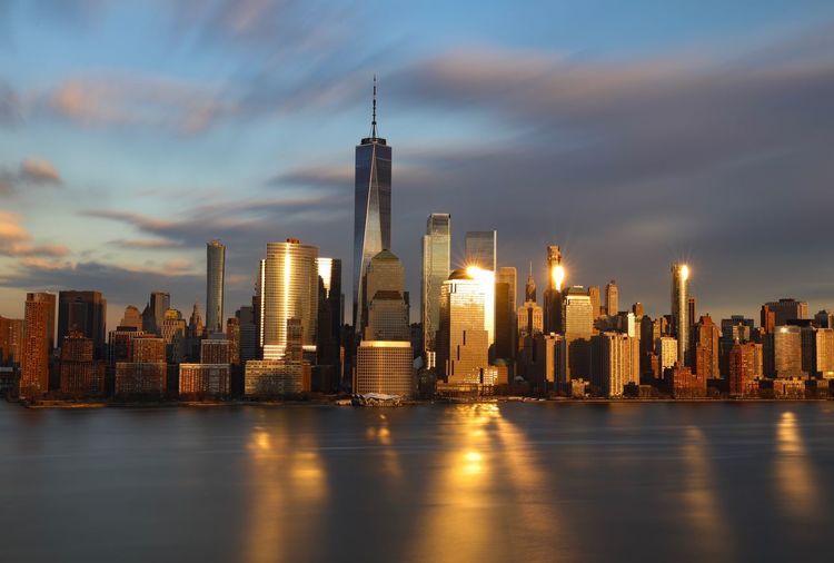 Illuminated buildings in city against cloudy sky