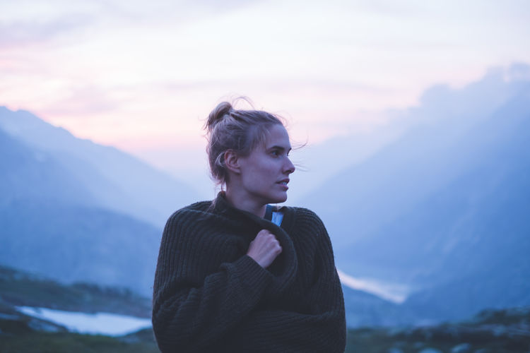 Portrait of young woman looking away against sky during sunset