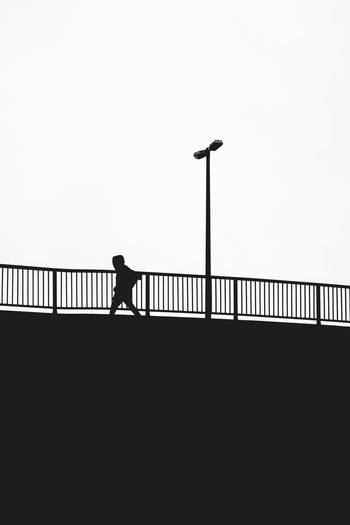 Silhouette man walking on staircase against clear sky