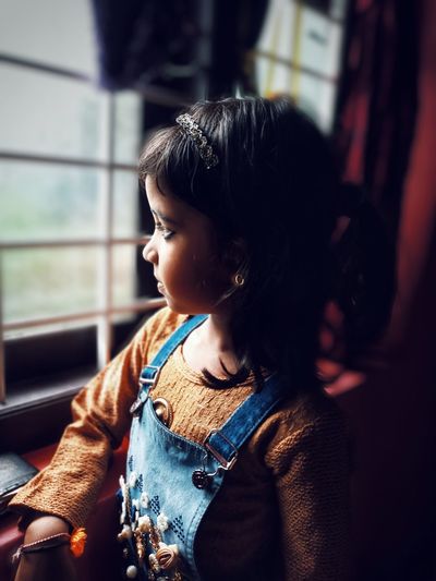 Close-up of girl looking through window