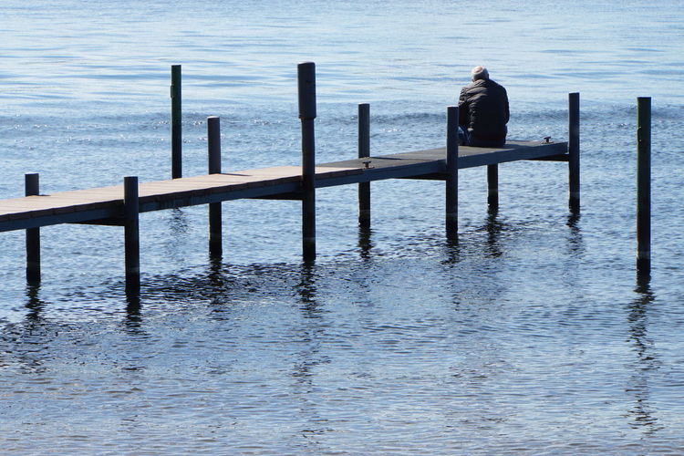 Man standing on railing by sea