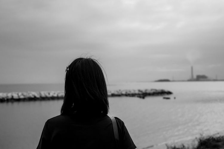 Rear view of woman by sea against sky