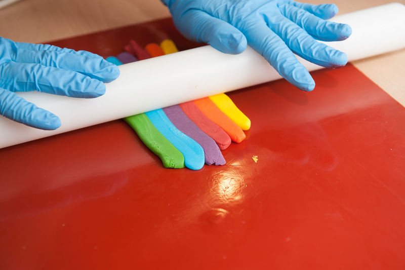 Cropped hand of person rolling colorful clay on table