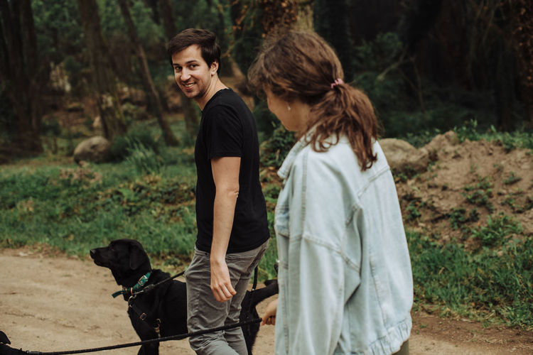 Young man looking back over shoulder at a woman while walking dogs