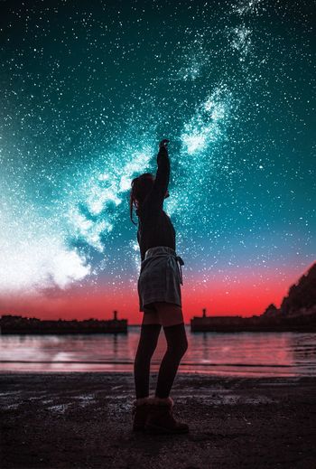 Full length of woman standing at beach against starry sky