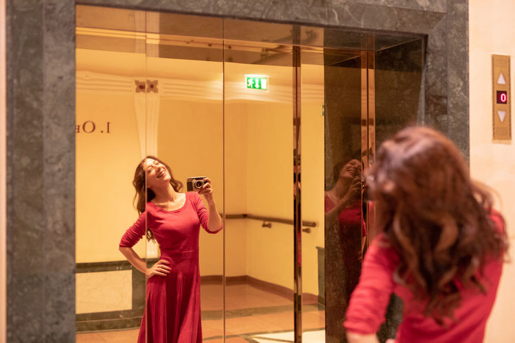 Happy woman taking photograph in mirror