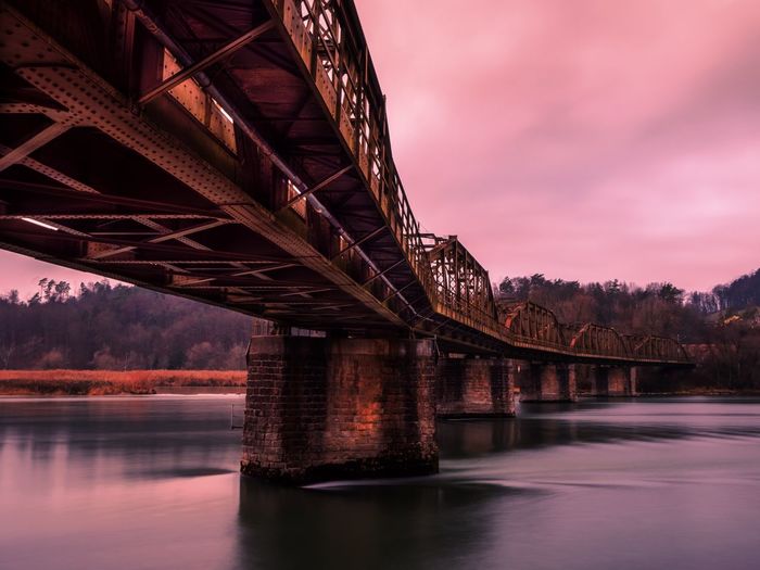 Low angle view of bridge over river at sunset