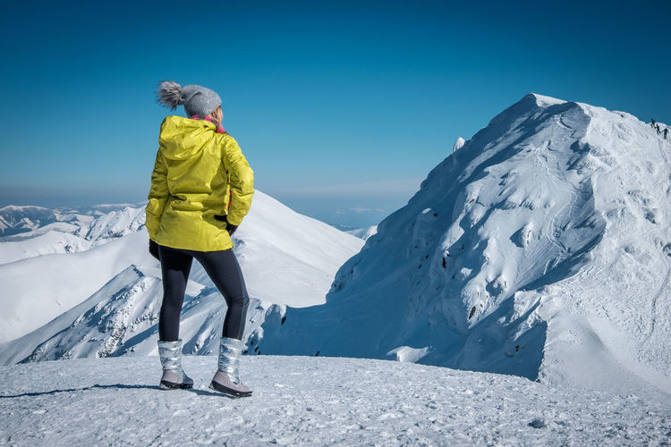 Rear view of woman standing on snowcapped mountain