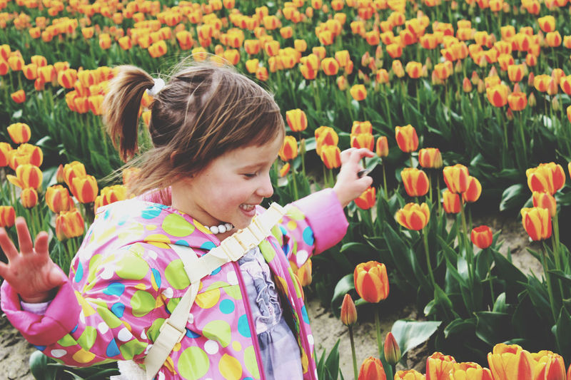 Side view of little girl with a ponytail running on tulip field.