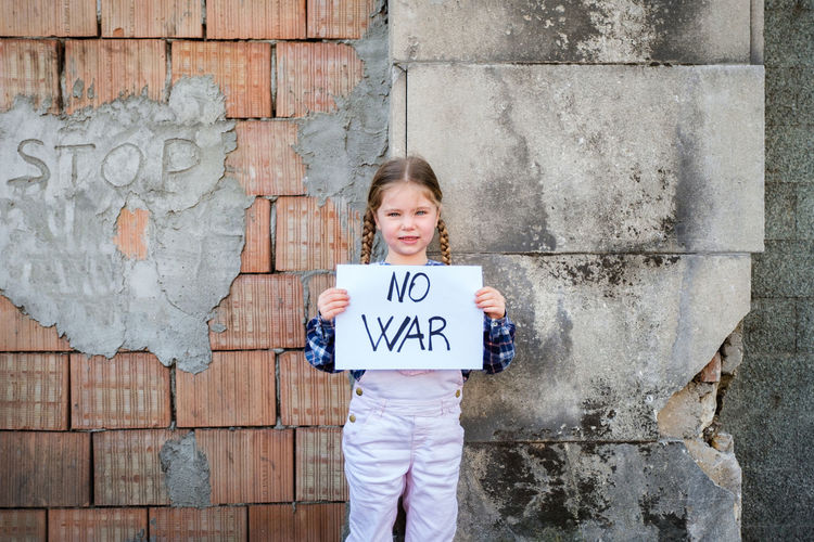 Portrait of girl holding poster against wall