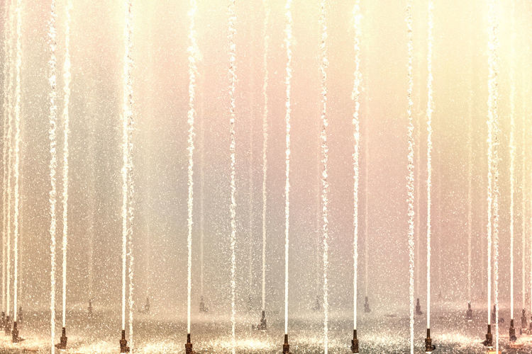 Background of multicolored jets and splashes of a fountain in the park.