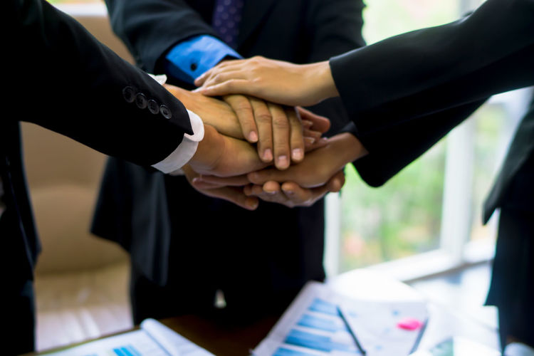 Cropped image of business people stacking hands in office