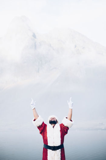 Man wearing santa claus costume standing against lake during foggy weather