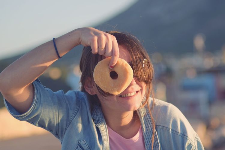 Close-up of smiling young woman holding donut