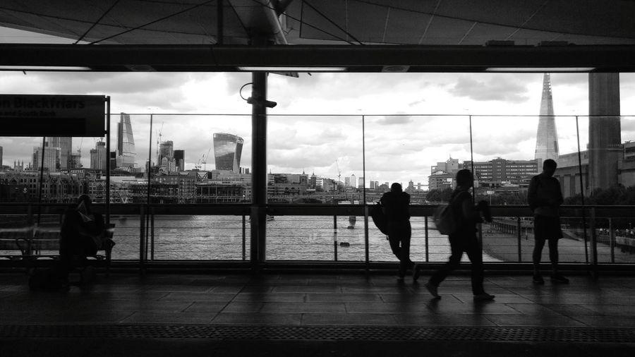 Silhouette people walking on bridge in city
