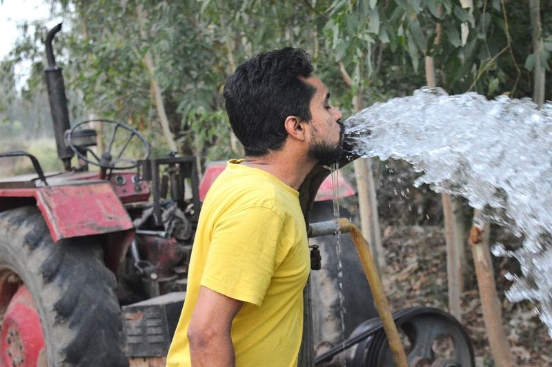 Side view of man drinking water at farm