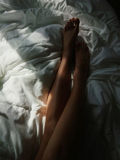 Low section of seductive woman lying on bed