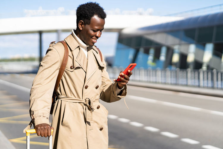 Young man using mobile phone while standing on bridge