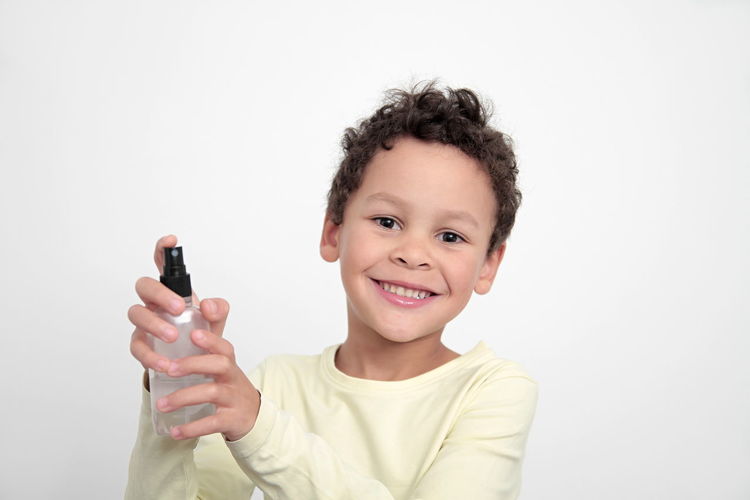Portrait of smiling boy holding hands against white background