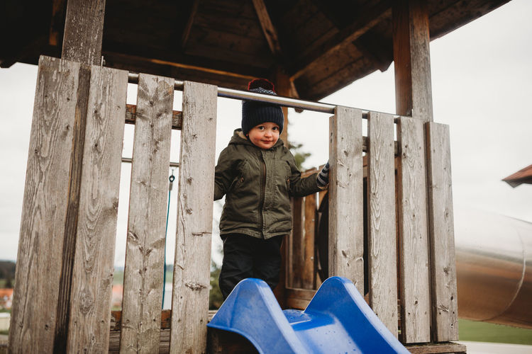 Young child on a wooden house at playground in winter