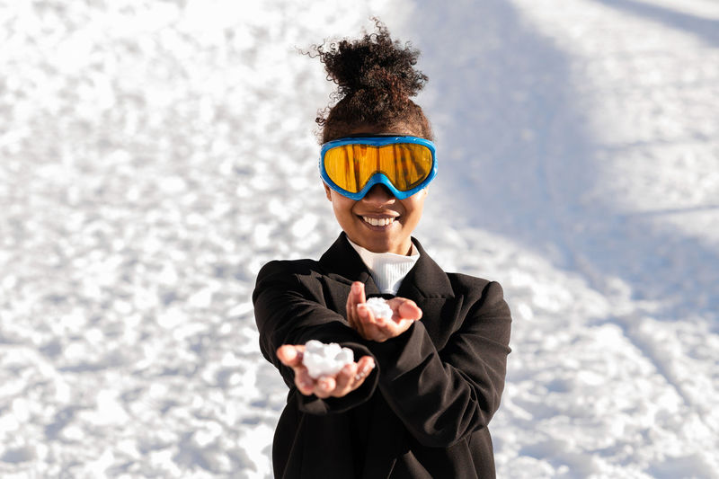 African american woman with protective glasses on a snowy mountain during winter