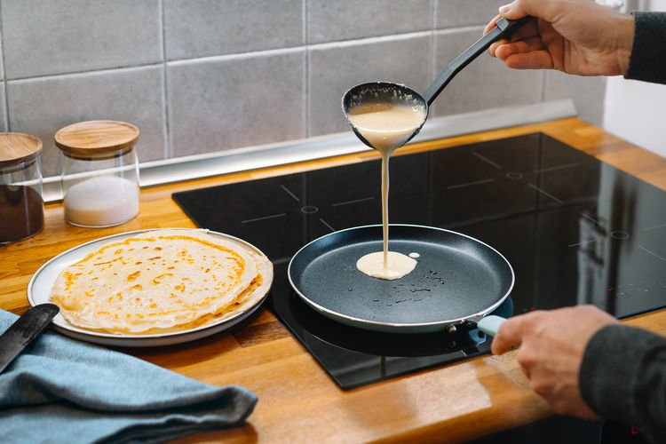 Midsection of person cooking pancakes in kitchen