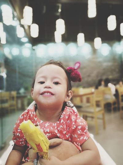 Portrait of cute girl having popsicle while sitting in illuminated restaurant