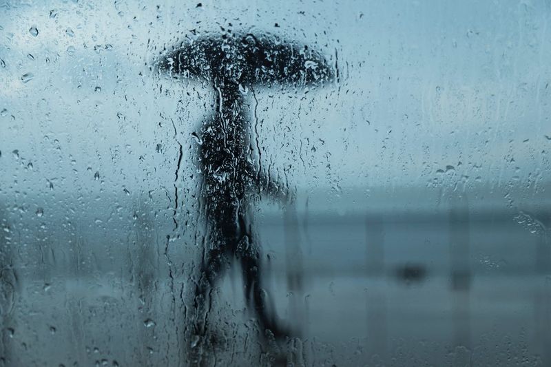 Person seen through of wet glass window in rainy season