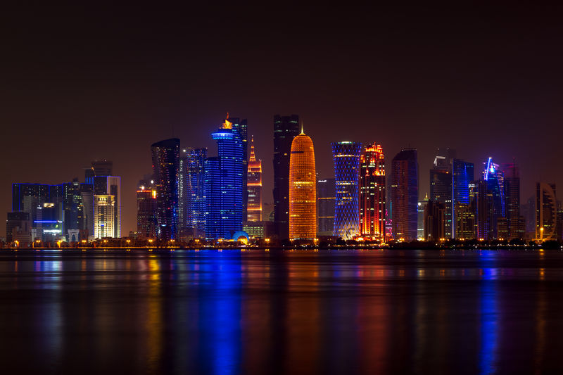Coloful illuminated skyline of doha at night, qatar, middle east against dark sky